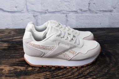 Beyaz kadının Reebok marka ayakkabıları beyaz tuğla bir duvarın yanında. Spor ve günlük ayakkabılar..