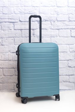 Tekerlekli bavul tuğla duvarın önünde duruyor..