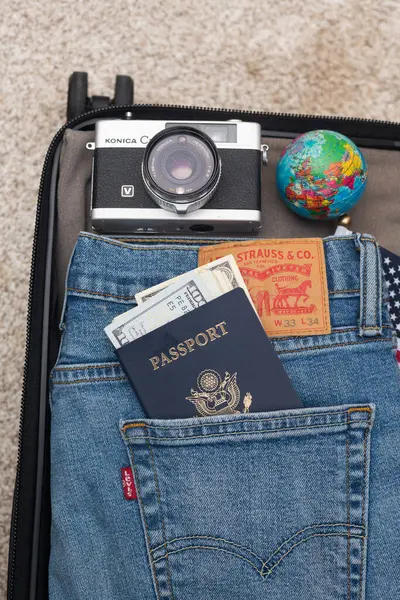 スーツケースは旅行のために梱包されています レビーズジーンズ アメリカのパスポートとドル カメラなど ロイヤリティフリーのストック写真