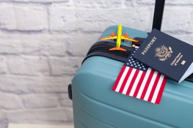 Bir Amerikan pasaportu bir bavulun üzerinde Amerikan bayrağı ve oyuncak bir uçağın yanında duruyor..