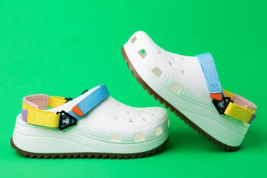 Yeşil arka planda Crocs 'tan izole edilmiş lastik sandaletler.