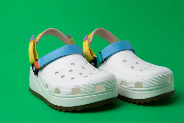 Weiße Crocs Sandalen Mit Farbigen Trägern Auf Grünem Hintergrund Stockbild