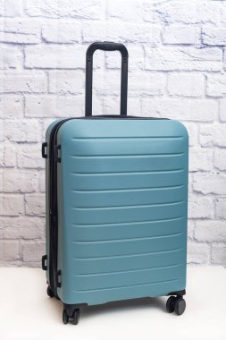 Tekerlekli bavul tuğla duvarın önünde duruyor..