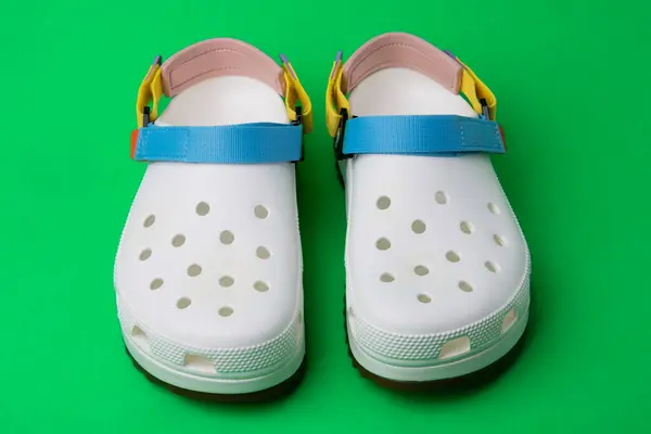 Vita Crocs Sandaler Med Färgade Remmar Grön Bakgrund Stockbild