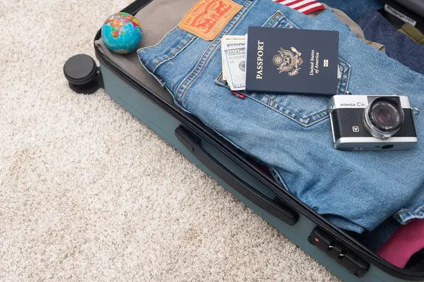 旅行箱装箱 莱维的牛仔裤 美国护照 美元和其他东西 旅行和自由概念 免版税图库照片