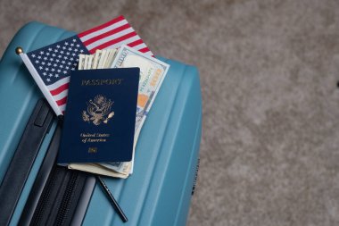 Amerikan vatandaşı pasaportu, Amerikan bayrağı ve doları seyahat bagajında yatıyor.