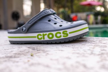 Gri Crocs sandaletleri havuzun kenarında yatıyor. Moda konforlu plaj ayakkabıları.