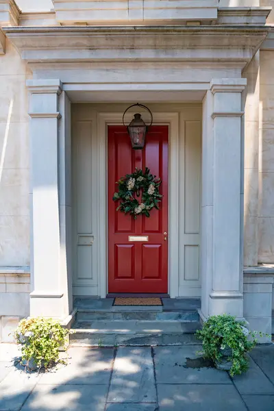 Stock image close-up of a whitewashed wall with a red wooden door and an overhanging balcony