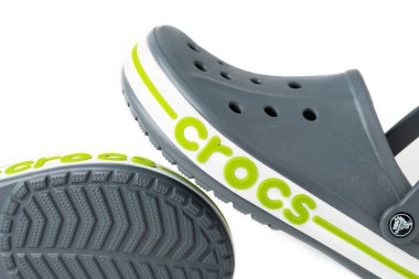 Beyaz arkaplanda yeşil KROKS yazılı gri Crocs sandaletleri..