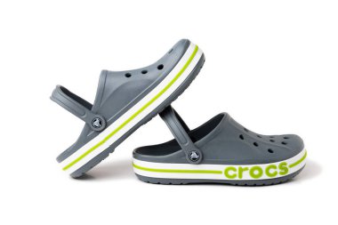 Beyaz arkaplanda yeşil KROKS yazılı gri Crocs sandaletleri..