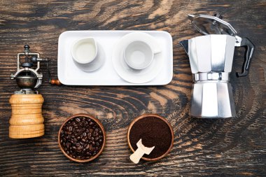 Gayzer kahve makinesi, kahve çekirdeği, kahve öğütücü ve bir kafe için krema. Karanlık masa, üst manzara..