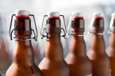 Bugel tıkaçlı bir şişe boynu. Işığa tutulmuş bir sıra kahverengi cam şişe..