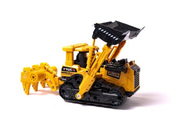 Beyaz arka planda izole edilmiş kovalı ve sabanlı sarı bir buldozer. İnşaat malzemelerinin oyuncak kopyası..