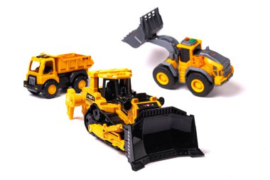 Sarı buldozer, beyaz arka planda çöp kamyonu ve yükleyici. İnşaat malzemelerinin oyuncak kopyası..