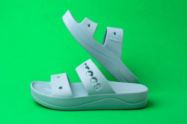 Yeşil arka planda izole edilmiş yaz terlikleri. yumuşak lastik sandaletler timsahlar. Yaz tatili moda ayakkabılar, sandaletler.