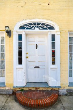 Sarı tuğlalı evin pencereleri olan beyaz ön kapı..