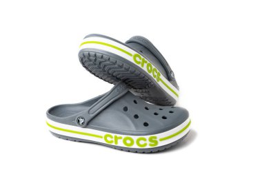 Yeşil CROCS yazıtlı gri sandaletler. Beyaz arka planda rahat unisex plaj ayakkabıları.