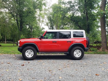 Kırmızı Ford Bronco Wildtrak bir orman yolunda park halinde..