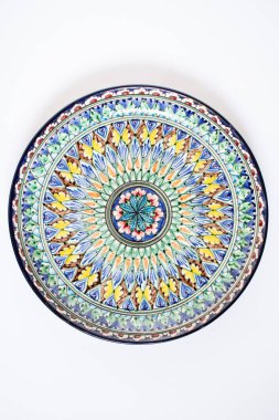 Beyaz arka planda ulusal süs olan çanak anten. Tabakta Asya desenleri var. Üst görünüm.