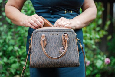 Bir kadının elinde fermuar olan modern Michael Kors çantası. Modaya uygun kadın aksesuarları..