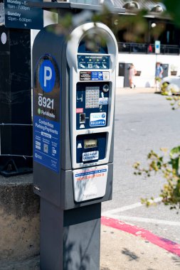 Şehir caddesinde bir otopark makinesi. Mobil başvuru ve banka kartlarında ödemeli park sistemi.