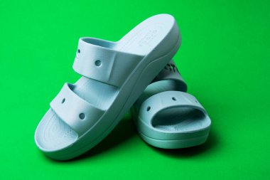 Yeşil arka planda izole edilmiş yaz terlikleri. yumuşak lastik sandaletler timsahlar. Yaz tatili moda ayakkabılar, sandaletler.