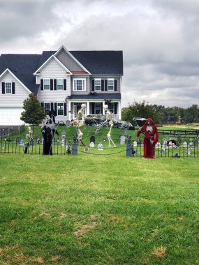 Cadılar Bayramı süslemeleri evin önündeki çimenlikte. İskeletler ve hayaletler korku ve korku ortamı yaratır..