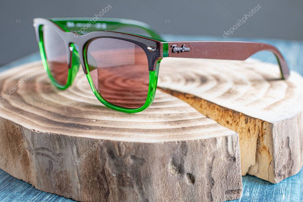Ray-Ban sunglasses with green frame on a wooden stump.