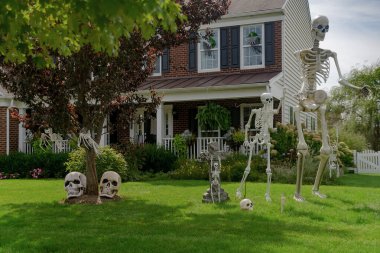 Cadılar Bayramı süslemeleri evin önündeki çimenlikte. İskeletler ve hayaletler korku ve korku ortamı yaratır..