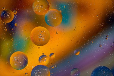 Sarı yağ kabarcıklarının makro fotoğrafları suda çözündü. Renkli arkaplan.