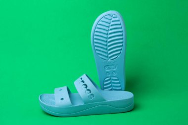 Yeşil arka planda izole edilmiş yaz terlikleri. yumuşak lastik sandaletler timsahlar. Yaz tatili moda ayakkabılar, sandaletler.