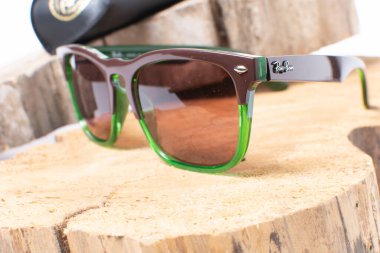 Ahşap arka planda yeşil çerçeveli Ray-Ban güneş gözlüğü. Popüler ve modaya uygun aksesuarlar.