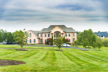  Mavi gökyüzünün altında büyük bir kır evi. Bahçe tasarımı, çimenlik ve bulutlu manzara.