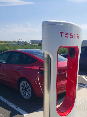 Tesla elektrikli arabası, yüksek hızlı akü şarjı için bir rıhtım istasyonuna park edilmiş.