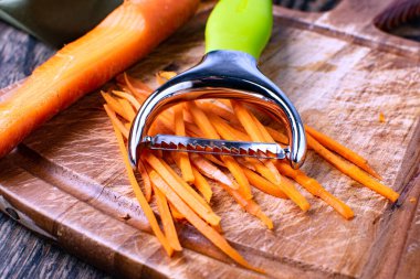 Tahtada doğranmış havuç ve öğütücü rendesi var..