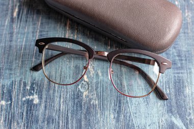 Klasik optik gözlükler ve mavi bir masanın üzerindeki çanta..