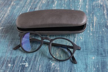 Pürüzsüz ve modern siyah çerçeveli gözlük ve gri gözlük mavi bir masada..