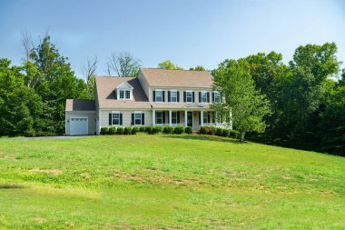 Geniş çimenlikli, çiftlik evi tarzı bir kır evinin güzel, modern dış görünüşü.