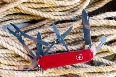 Swiss Knife multi-tool and ropes on an old wooden table. clipart