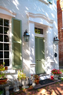 Girişte verandası ve feneri olan yeşil ahşap bir kapı. Çiçekler ve balkabaklarıyla süslenmiş..