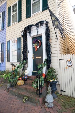 Geleneksel sonbahar tatili için dekore edilmiş eve giriş, kapıda çelenkler ve çelenkler, merdivenlerde balkabakları.
