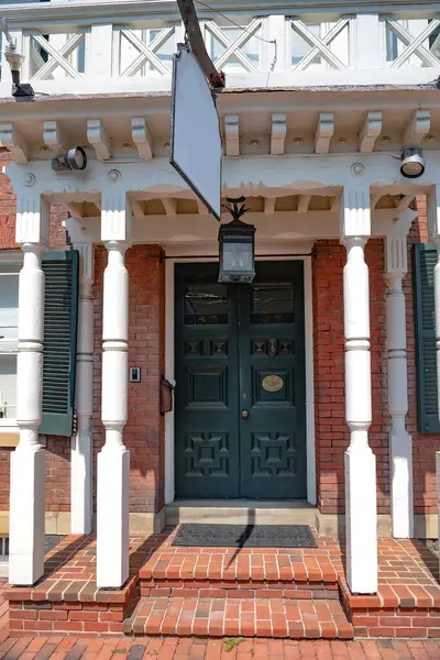 Girişte verandası ve feneri olan siyah ahşap bir ön kapı..