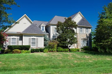 Geniş çimenlikli, çiftlik evi tarzı bir kır evinin güzel, modern dış görünüşü.