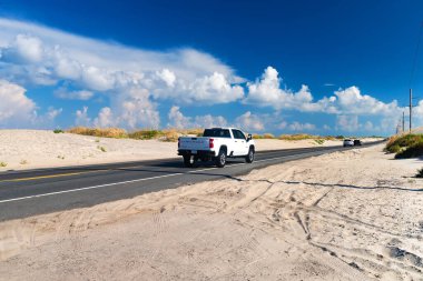 Chevrolet Silverado, Kuzey Carolina 'daki Atlantik kıyılarının kum tepeleri arasında hızla ilerliyor. Mavi gökyüzü ve kum,