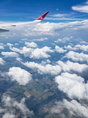 Türk havayolu şirketi Turkishaerline 'ın amblemiyle uçağın kanatları altında bulutlar ve mavi gökyüzü,