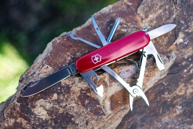 Bir taşın üzerinde yatarken Victorinox kırmızı klasik İsviçre çakısı tüm aletleri açık. 