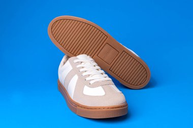 Mavi arka planda, Yastık markasından beyaz deri ayakkabılar..