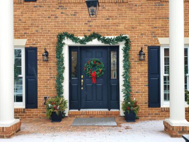 Karla kaplı veranda ve evin ön kapısı Noel tatili için dekore edilmiş..