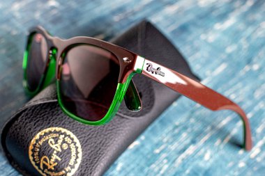Ray-Ban güneş gözlüğü ve deri çanta. Plastik yeşil gözlük çerçevesi.