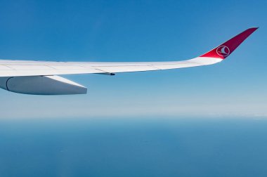 Türk hava yollarının amblemi olan uçağın kanadının altında açık mavi gökyüzü, metin için yer.